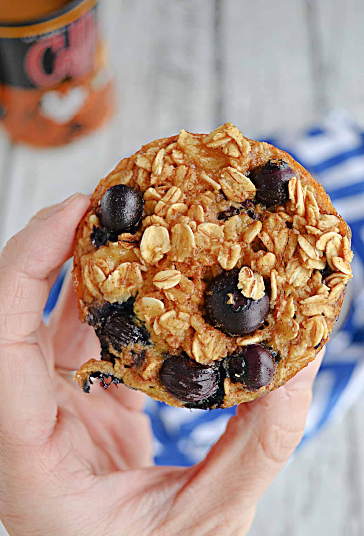 A hand holding an oatmeal cup with blueberries.