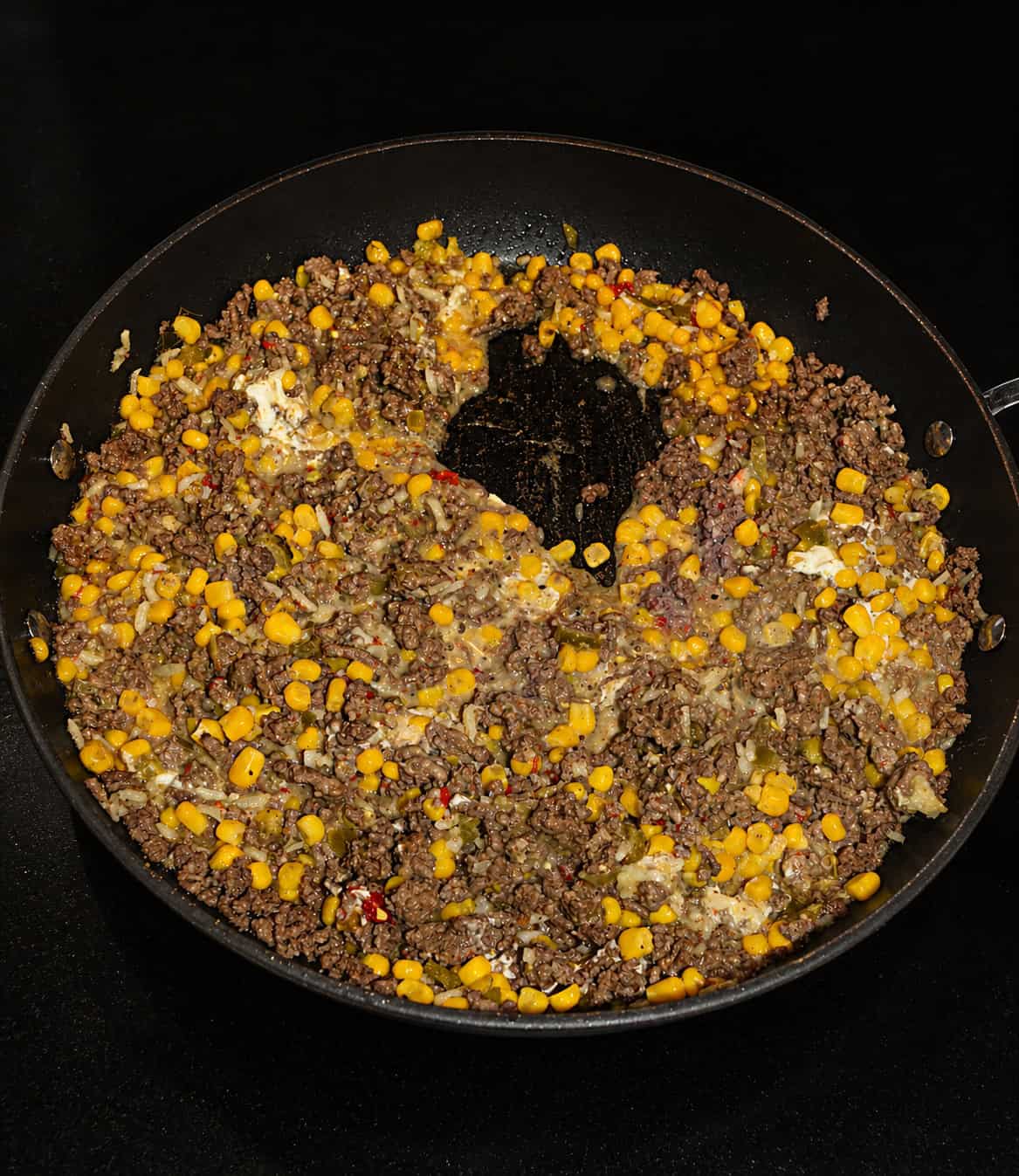 A skillet filled with beef and corn.