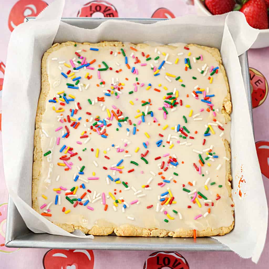 A pan of bar cookies with icing and sprinkle son top.