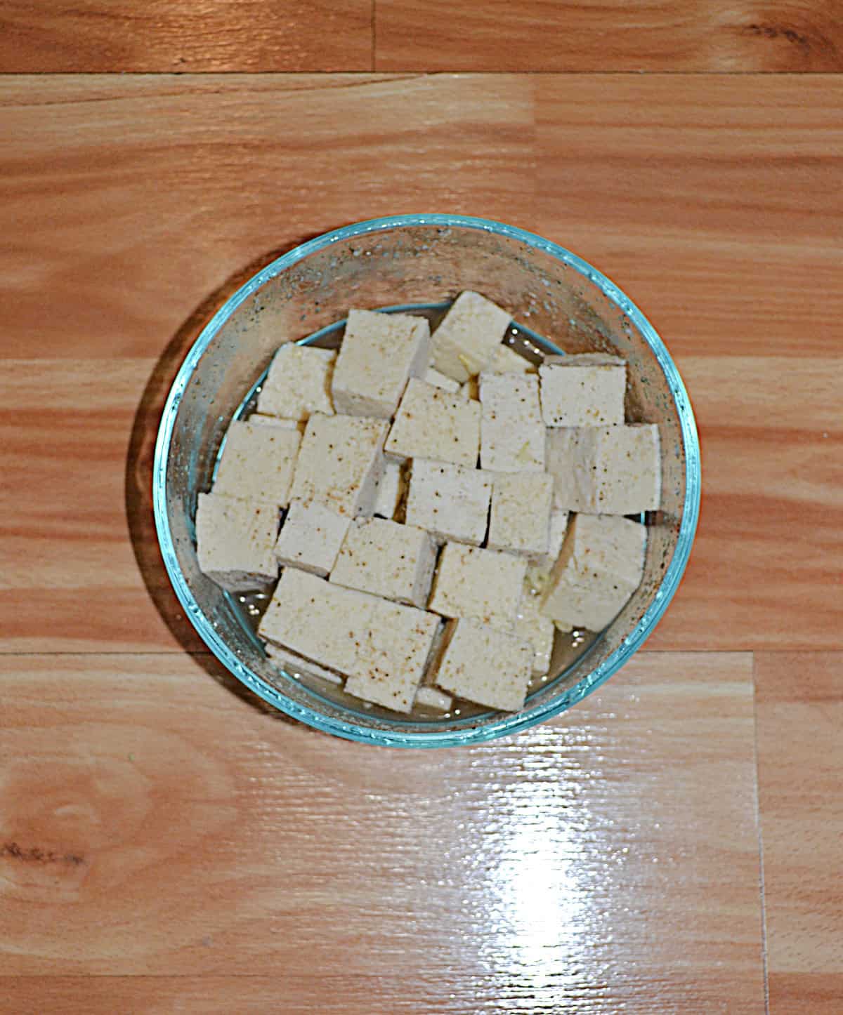 A bowl of tofu pieces in pickle juice.