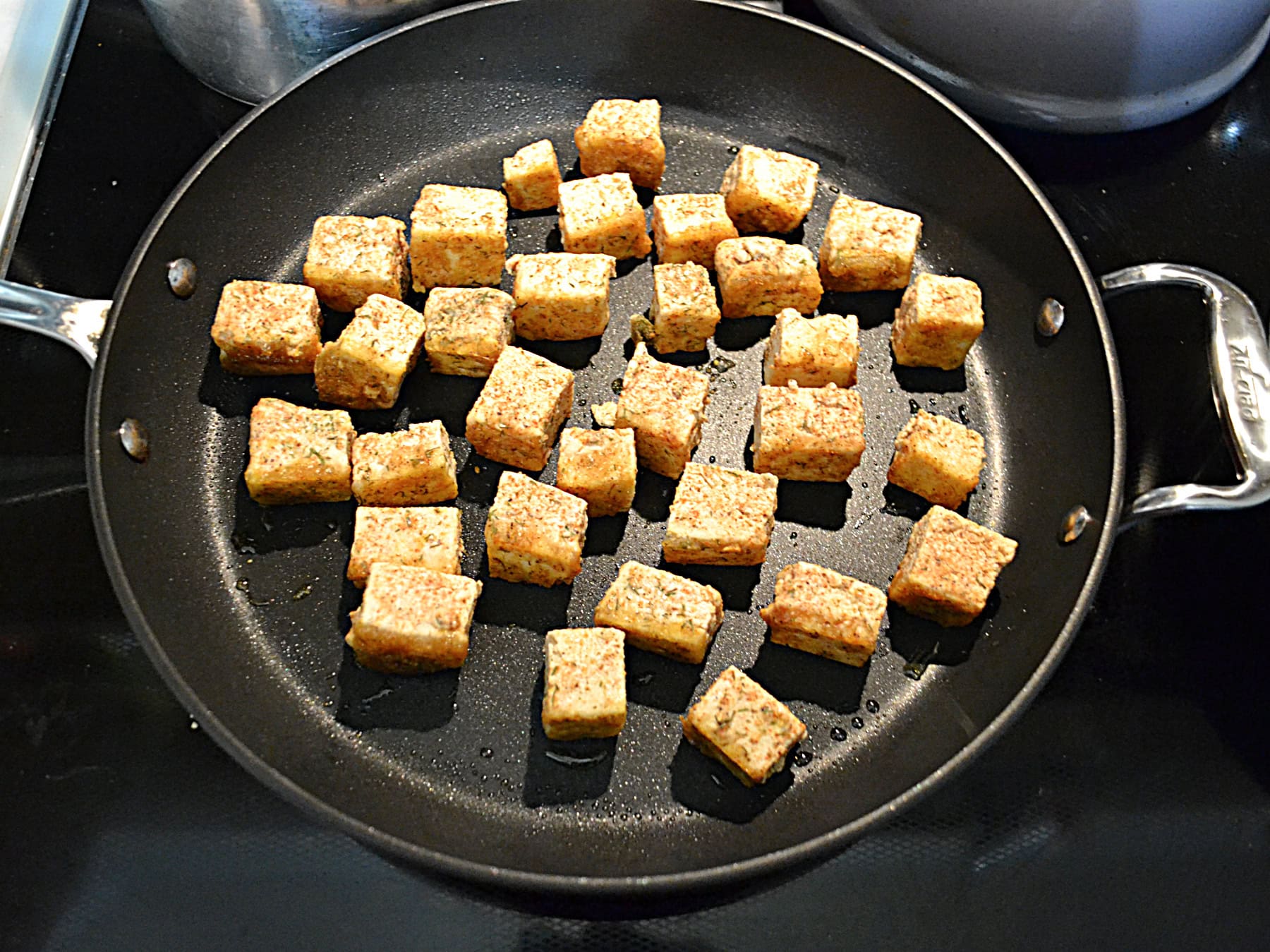 A saute pan with tofu bites in it.