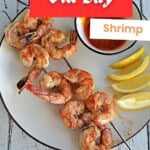 Pin Image: Title, a plate with grilled shrimp skewers, lemon wedges, and a bowl of cocktail sauce.