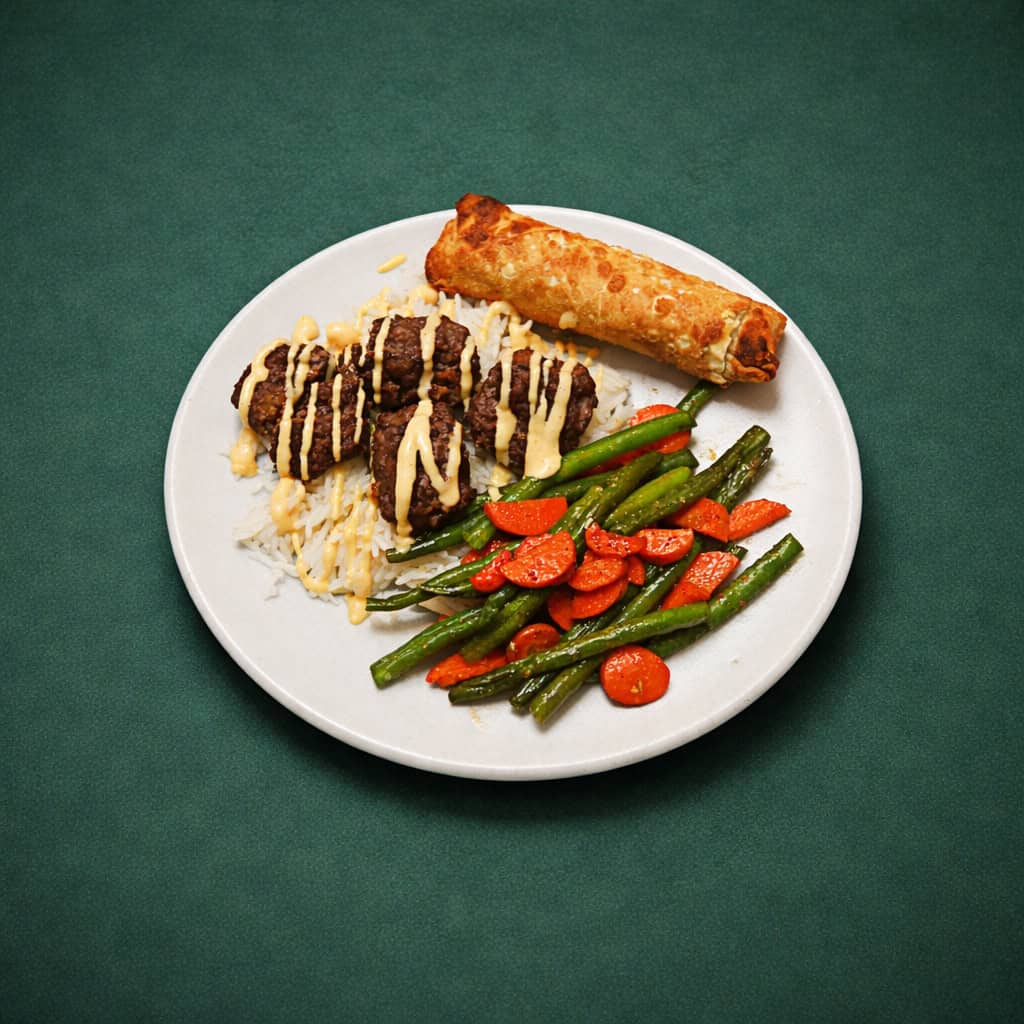 A plate with meatballs on rice with sauce on top, a pile of veggies, and an eggroll.