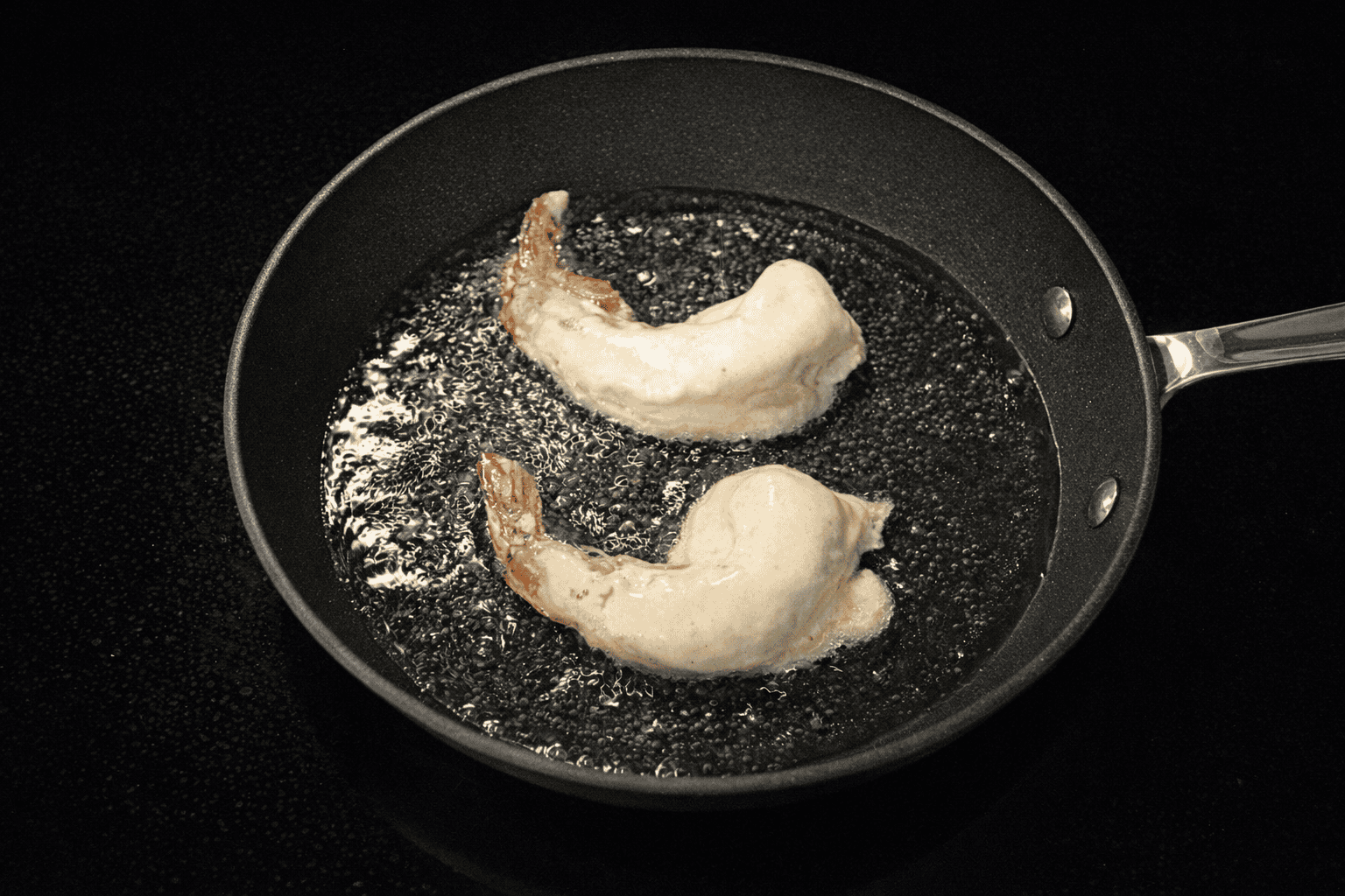 A pan with uncooked shrimp in it.