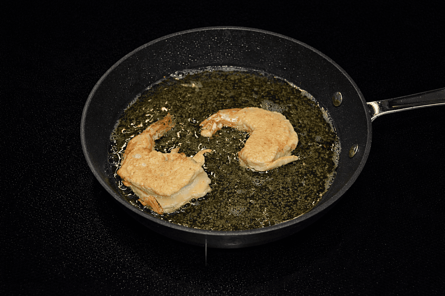 A pan with shrimp frying in oil.