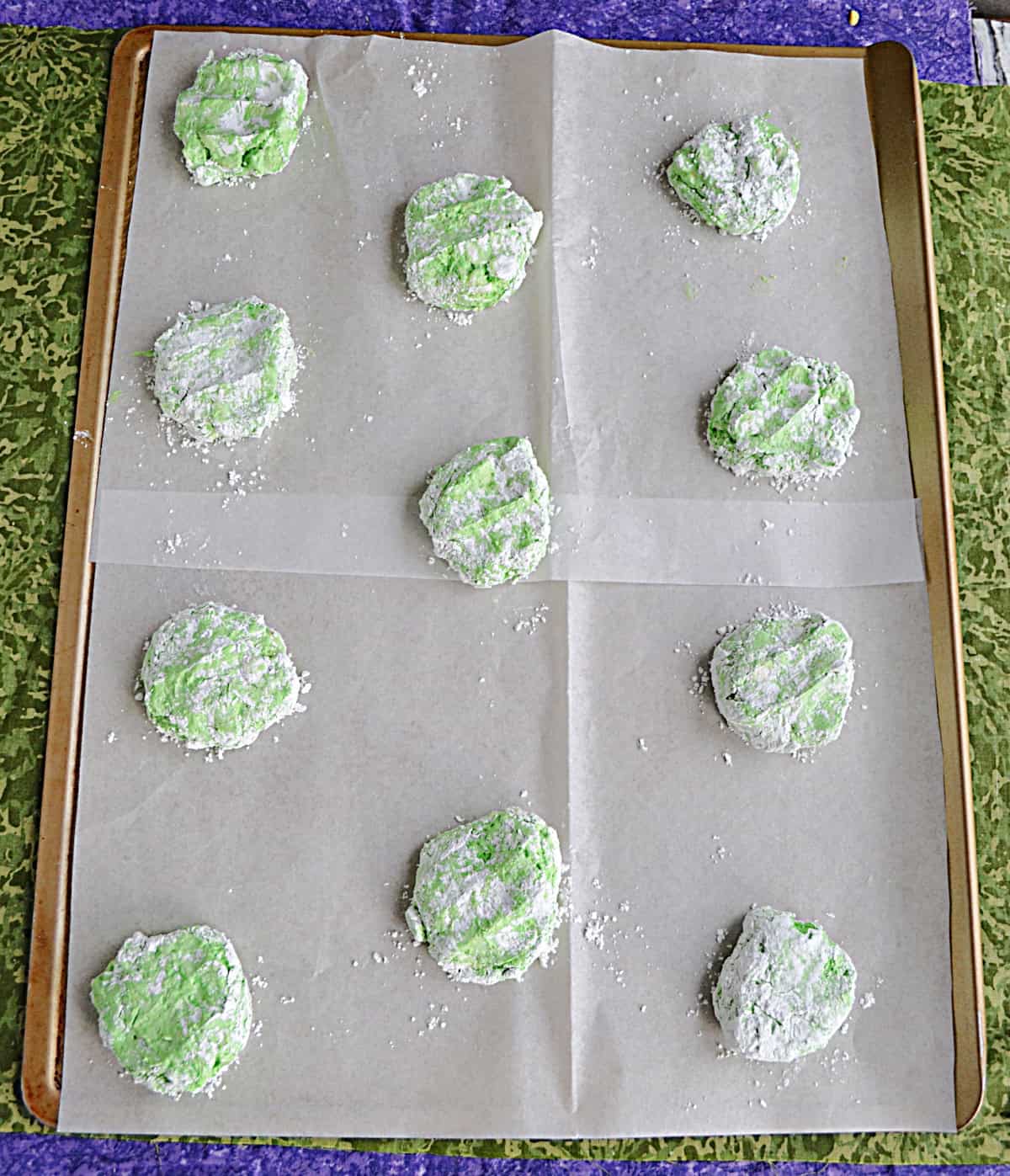 A baking sheet with light green cookie dough balls on it.