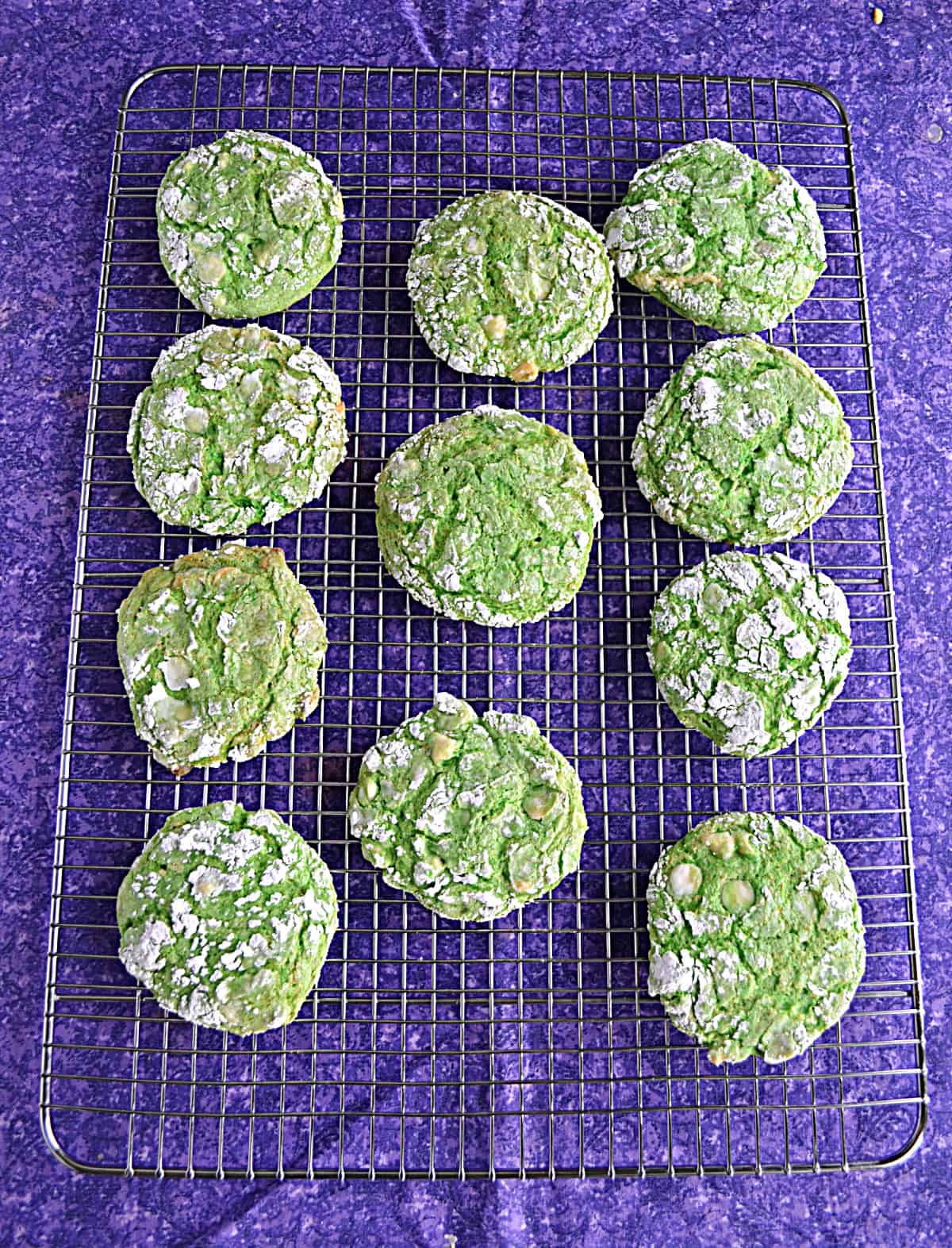 A baking rack with green cookies on it.