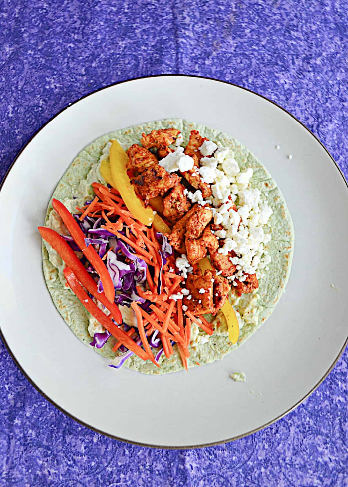 A wrap layered with feta, peppers and carrots, and chicken.