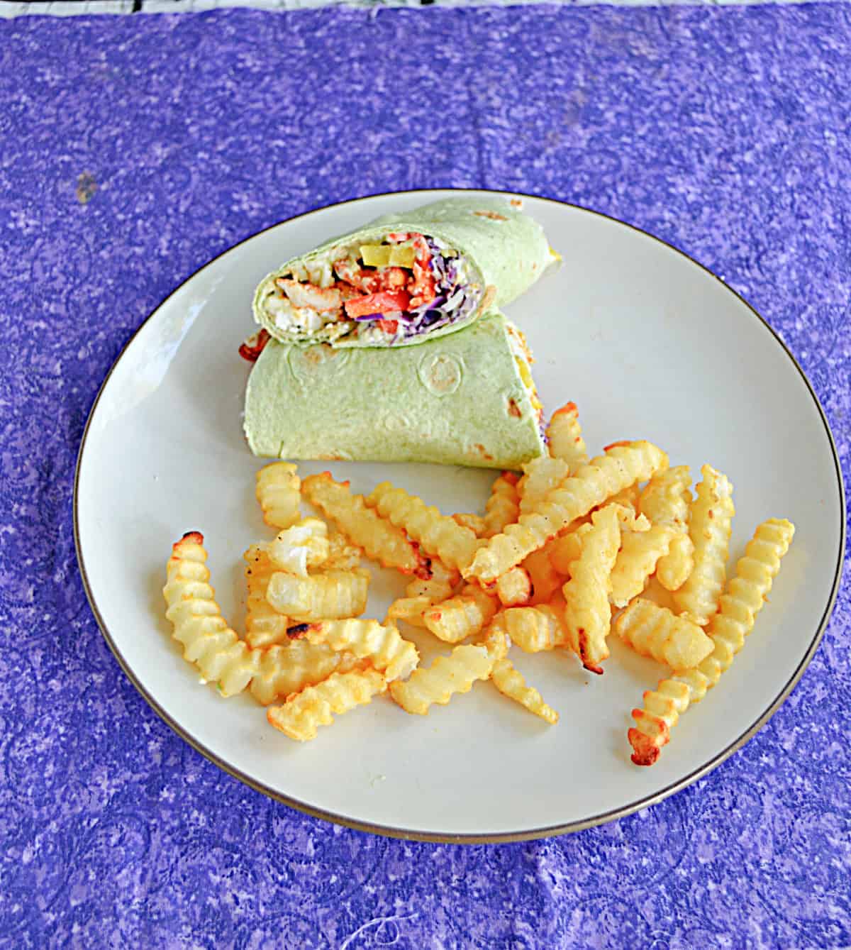 A plate with fries and a wrap cut in half on it.