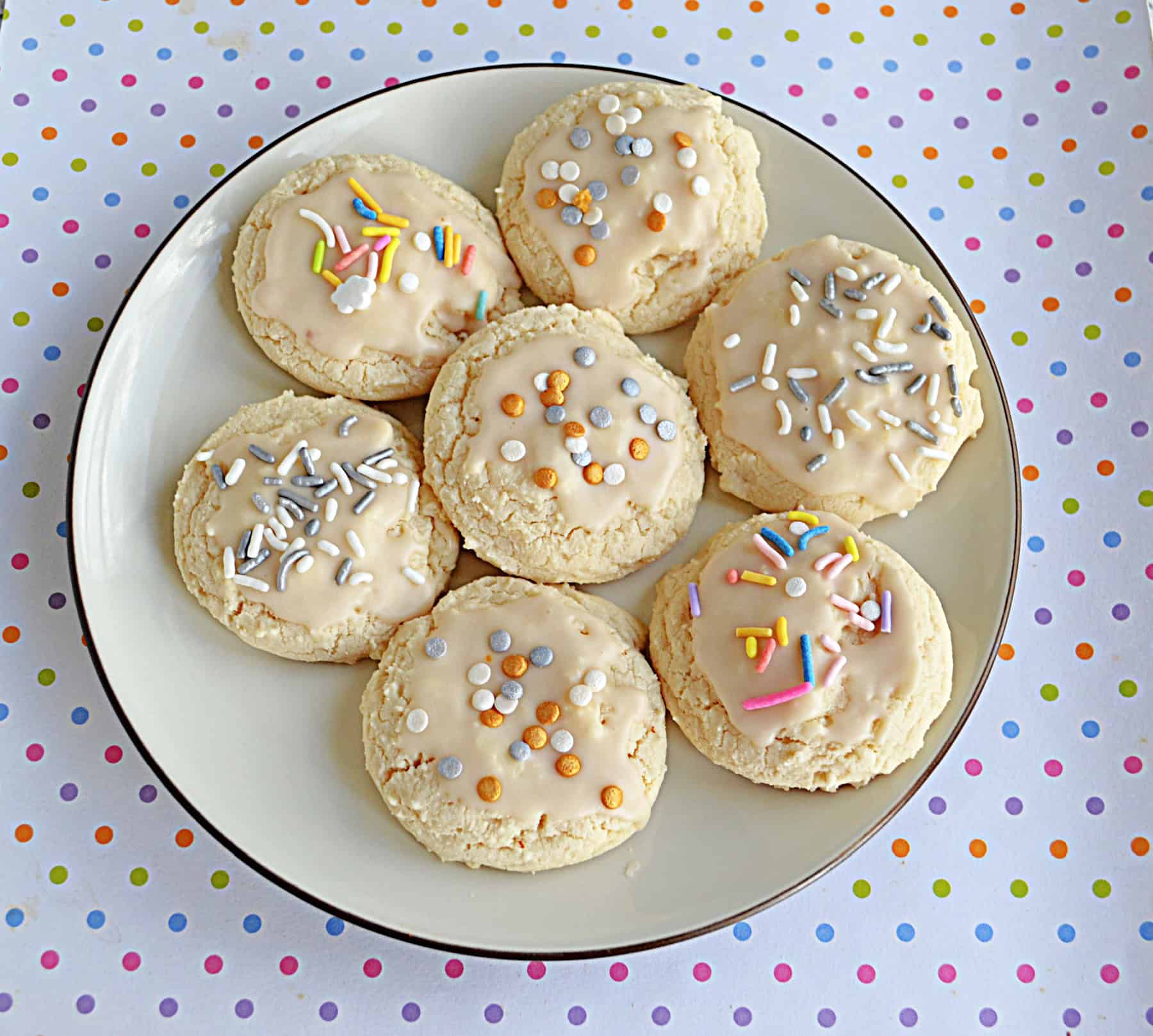 A plate of glazed cookies with sprinkles on top.