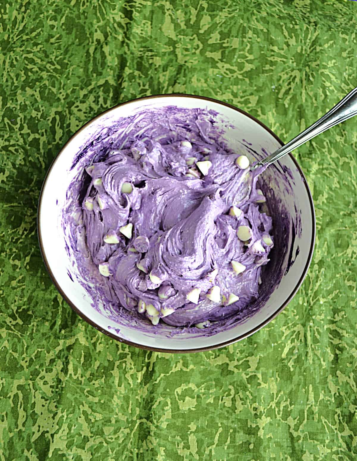 A bowl of purple cookie dough with a spoon in it.