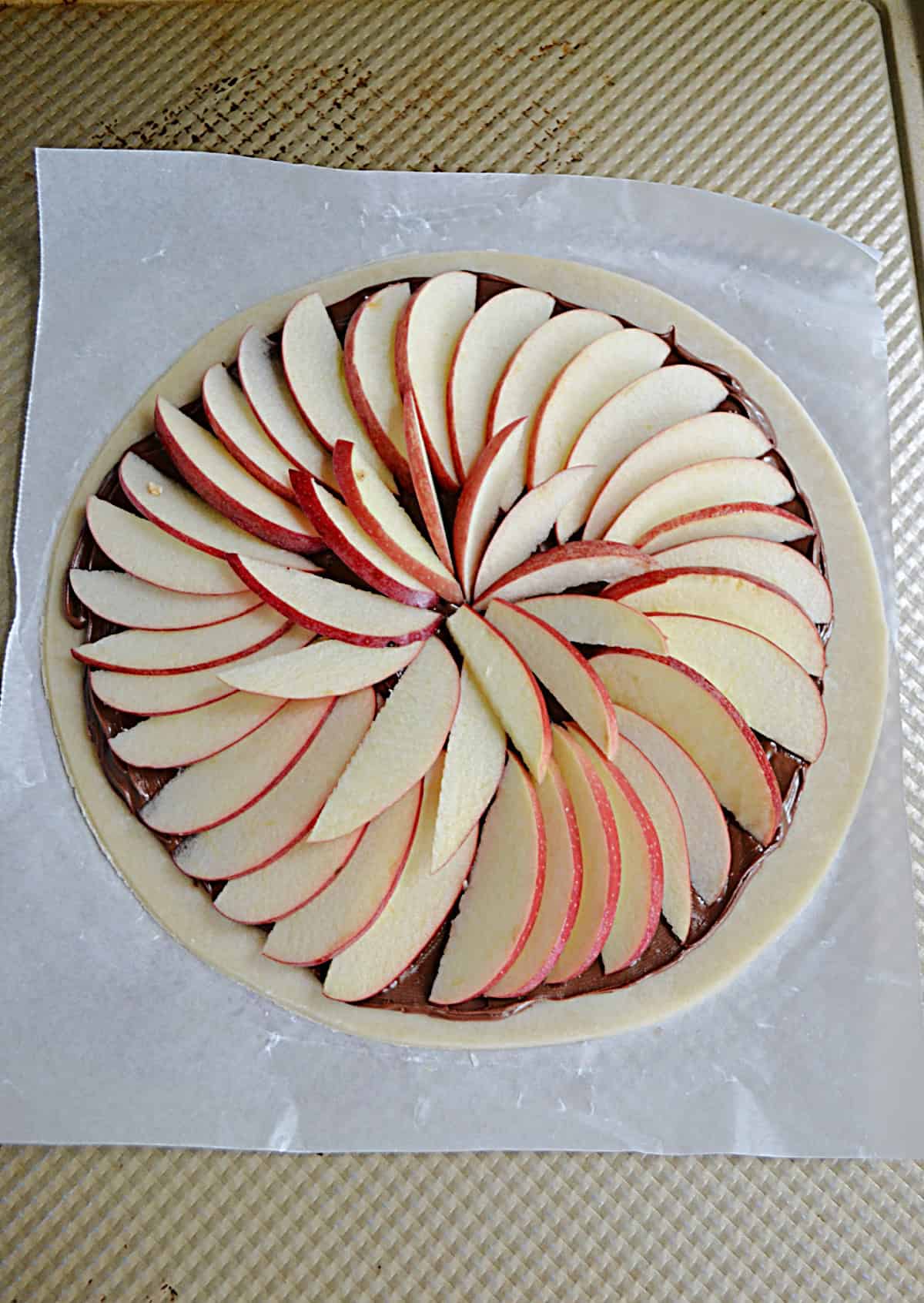 A pie crust topped with a spiral of thinly sliced apples.