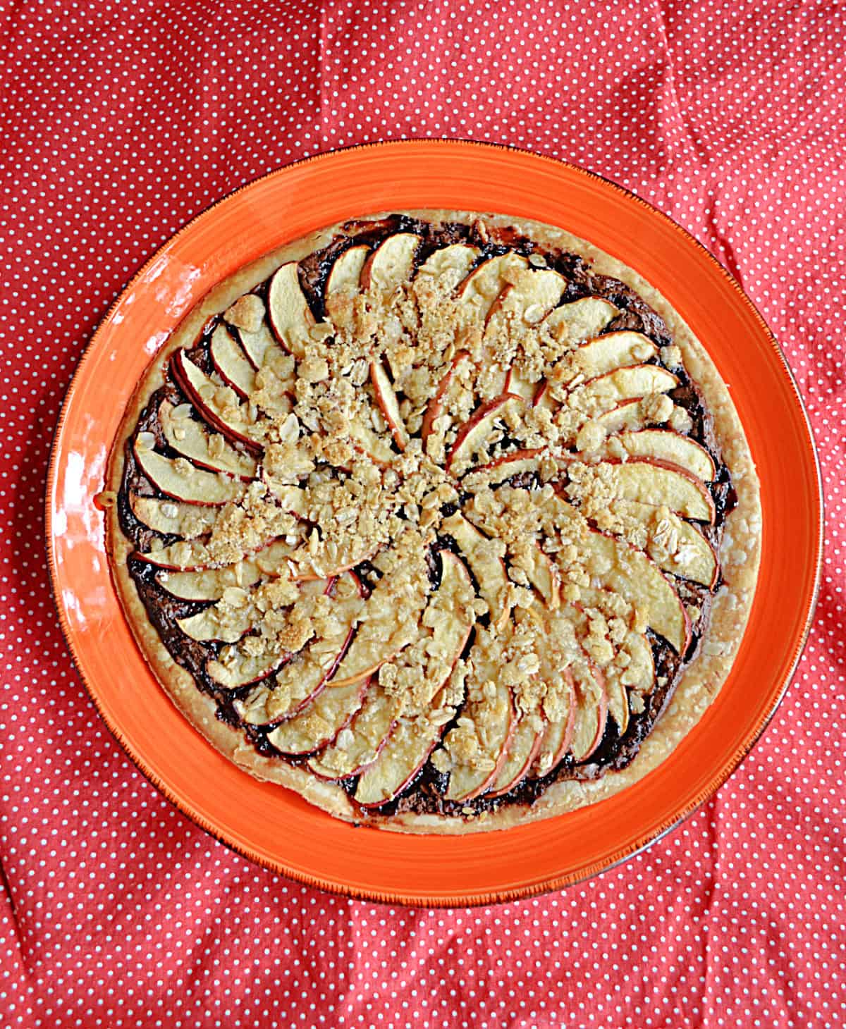 A dessert pizza with sliced apples and a golden crumble on top.