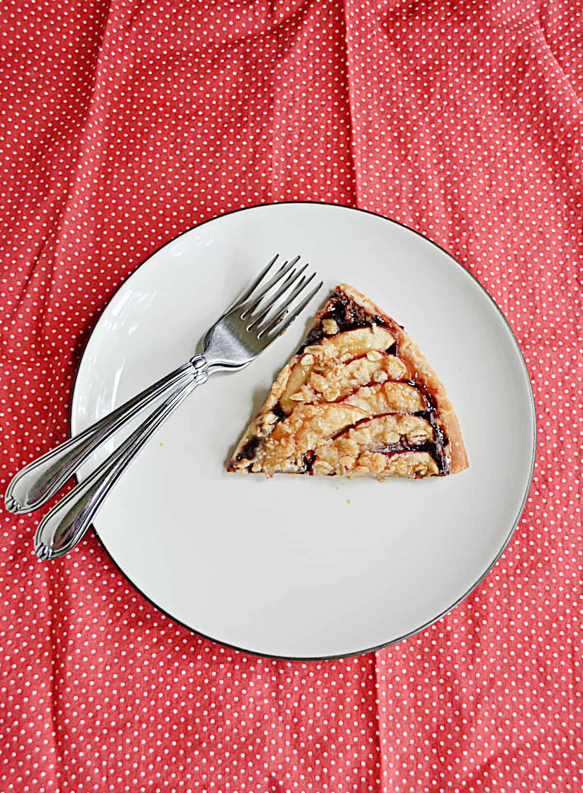 A plate with a slice of apple pizza on it and two forks.