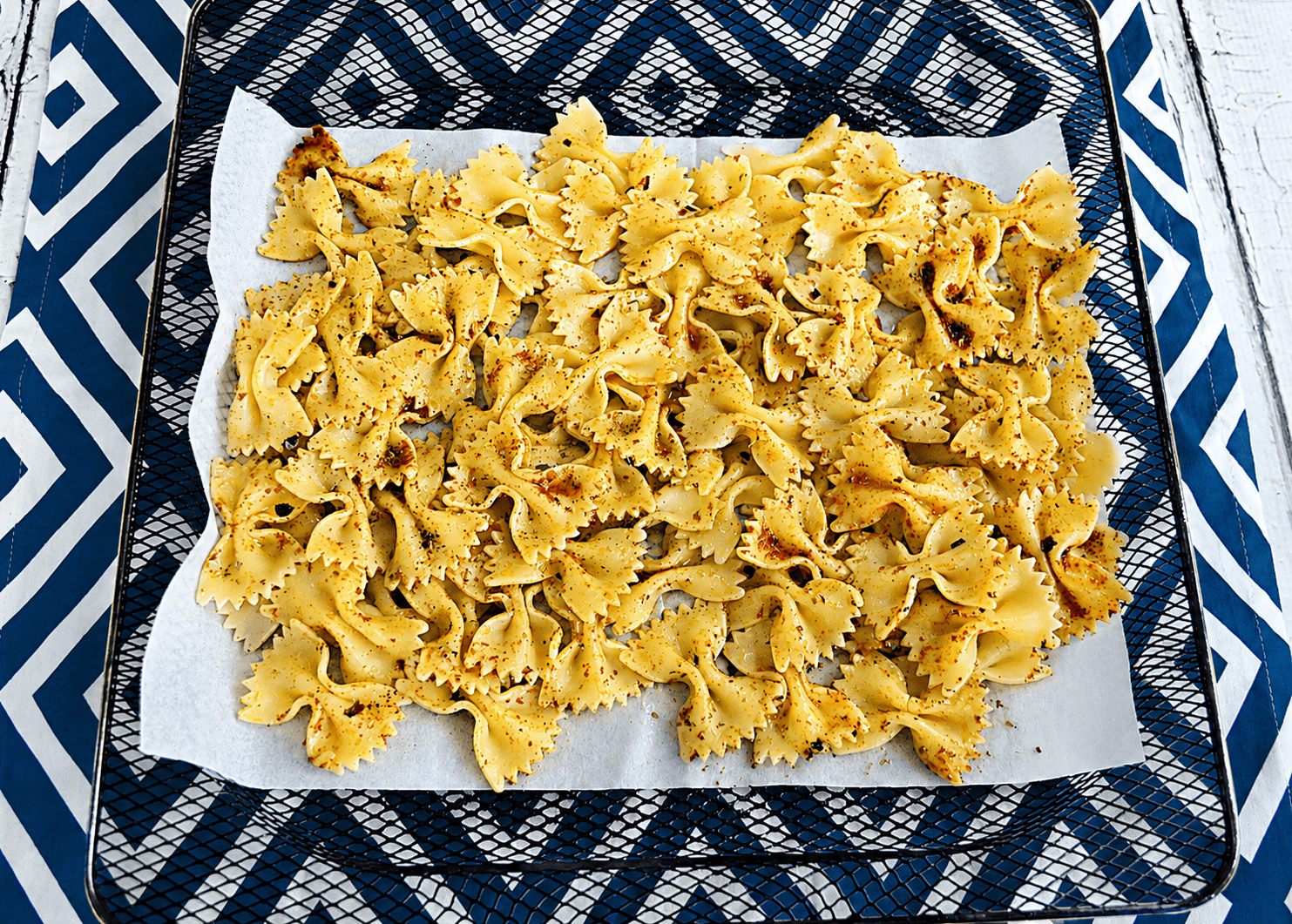 A pan of bow tie noodles and seasonings.