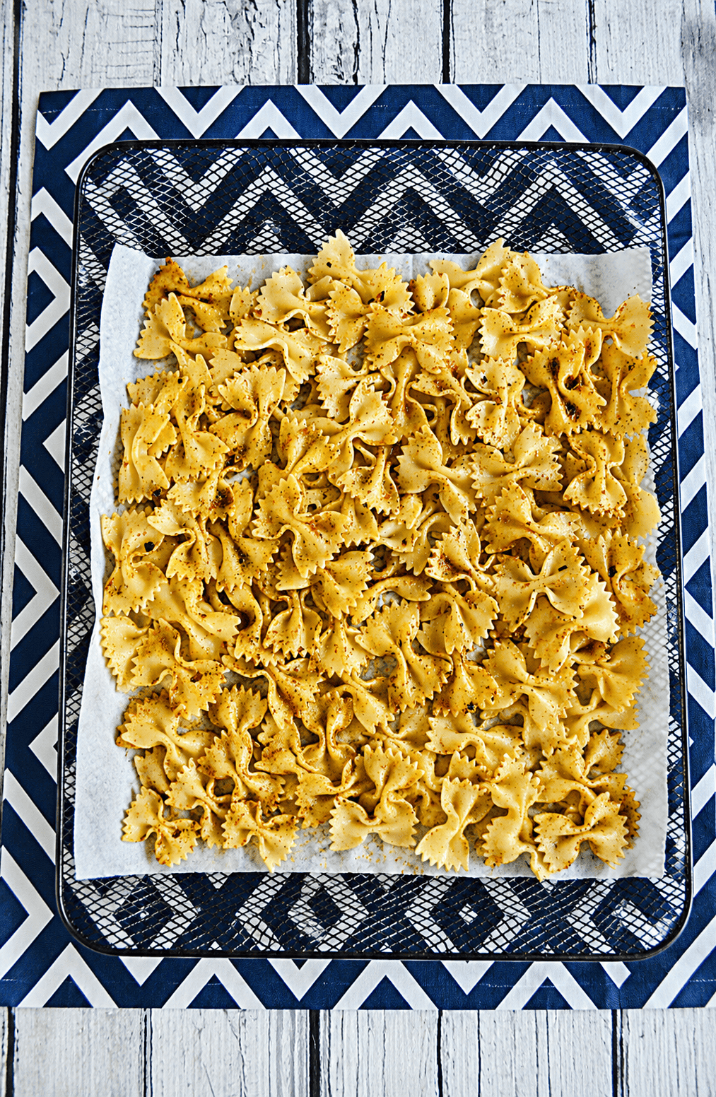 A pan of bow tie pasta and seasonings that are starting to brown.
