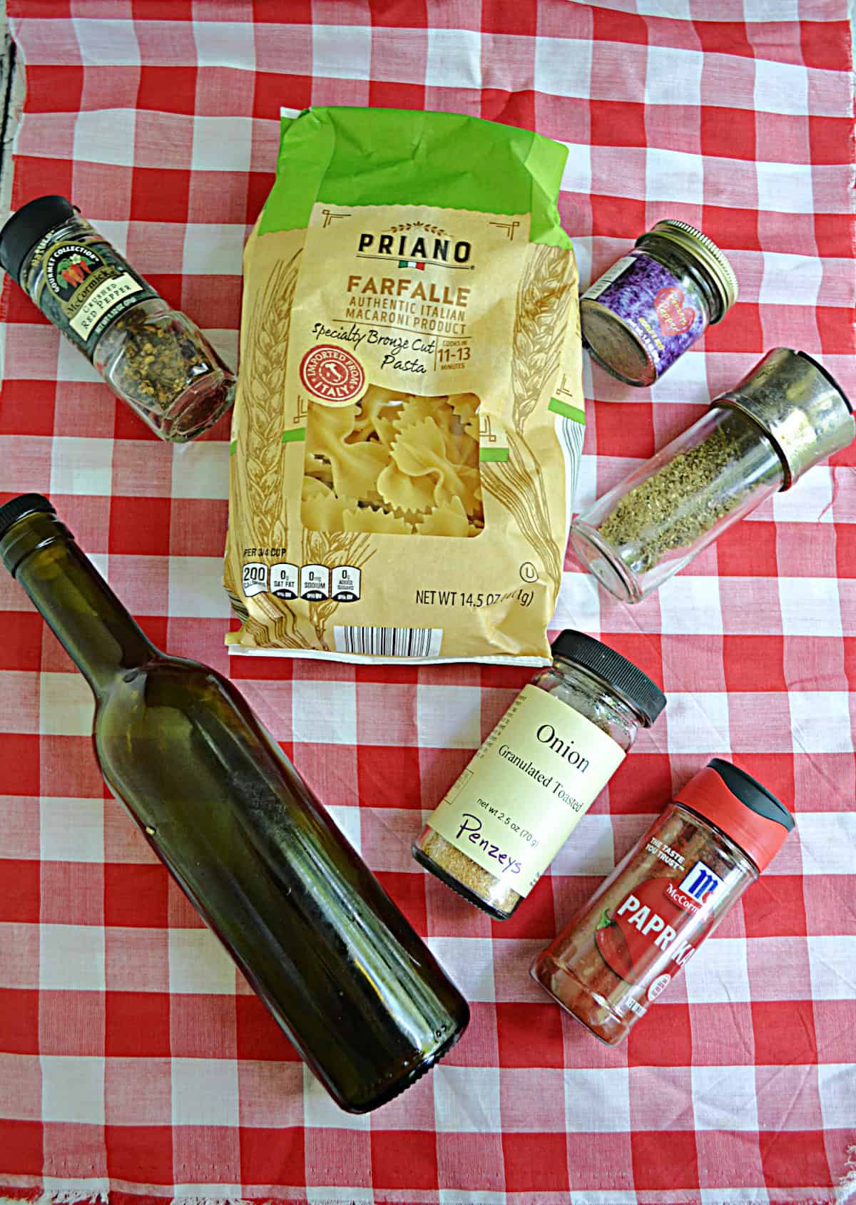A bottle of olive oil, a bag of pasta, a bunch of containers of seasonings.
