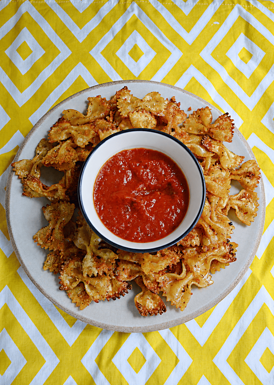 A plate of pasta chips with a bowl of marinara in the middle.