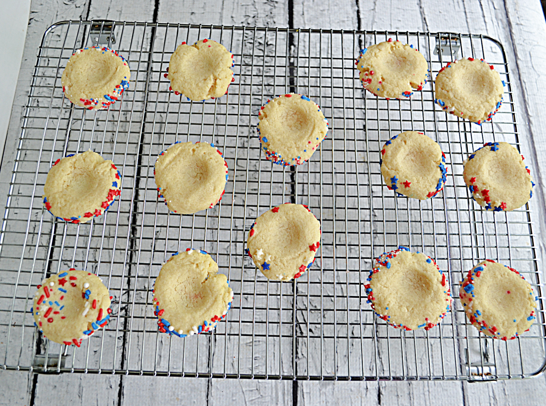 A wire rack with unfilled thumbprint cookies on it.
