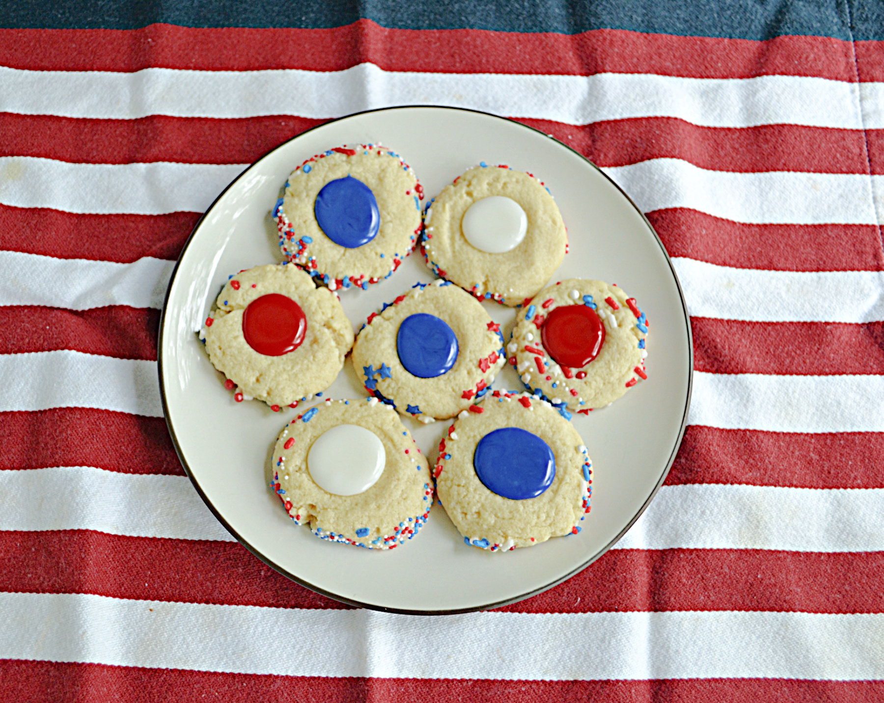 A plate of thumbprint cookies filled with red, white, or blue icing.
