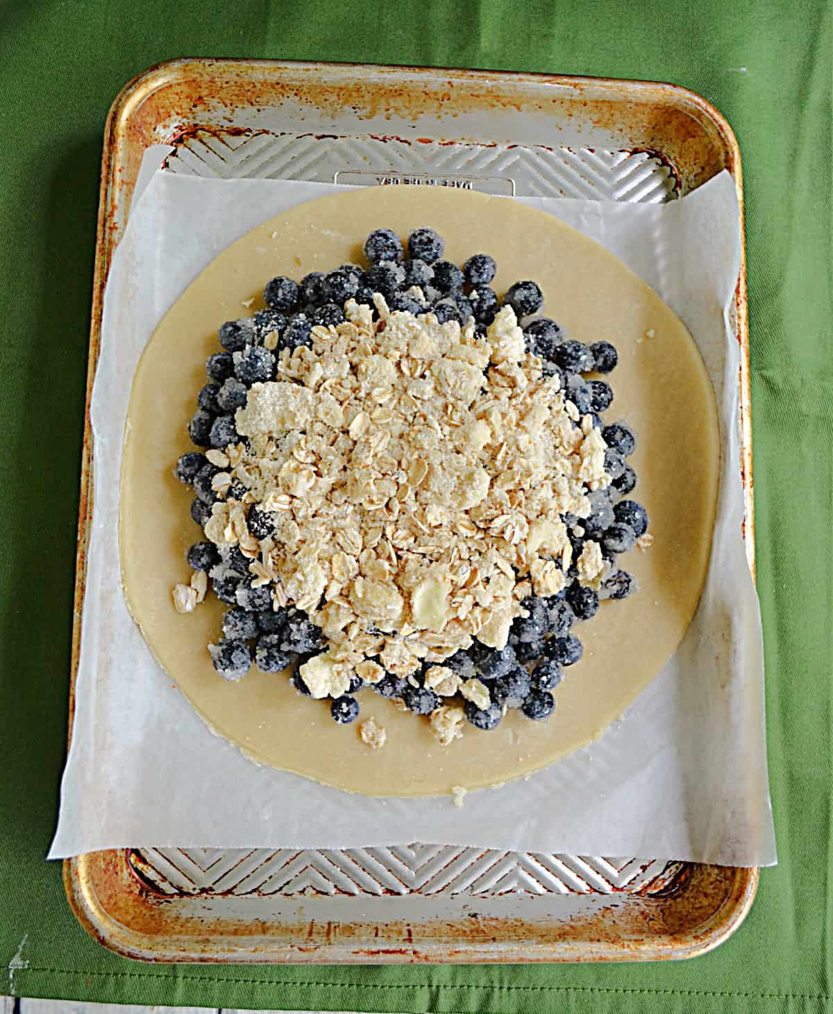 A dough circle with blueberries and a crumble topping.