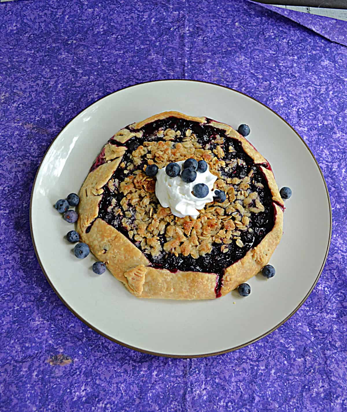 A blueberry galette with whipped cream on top on a plate.