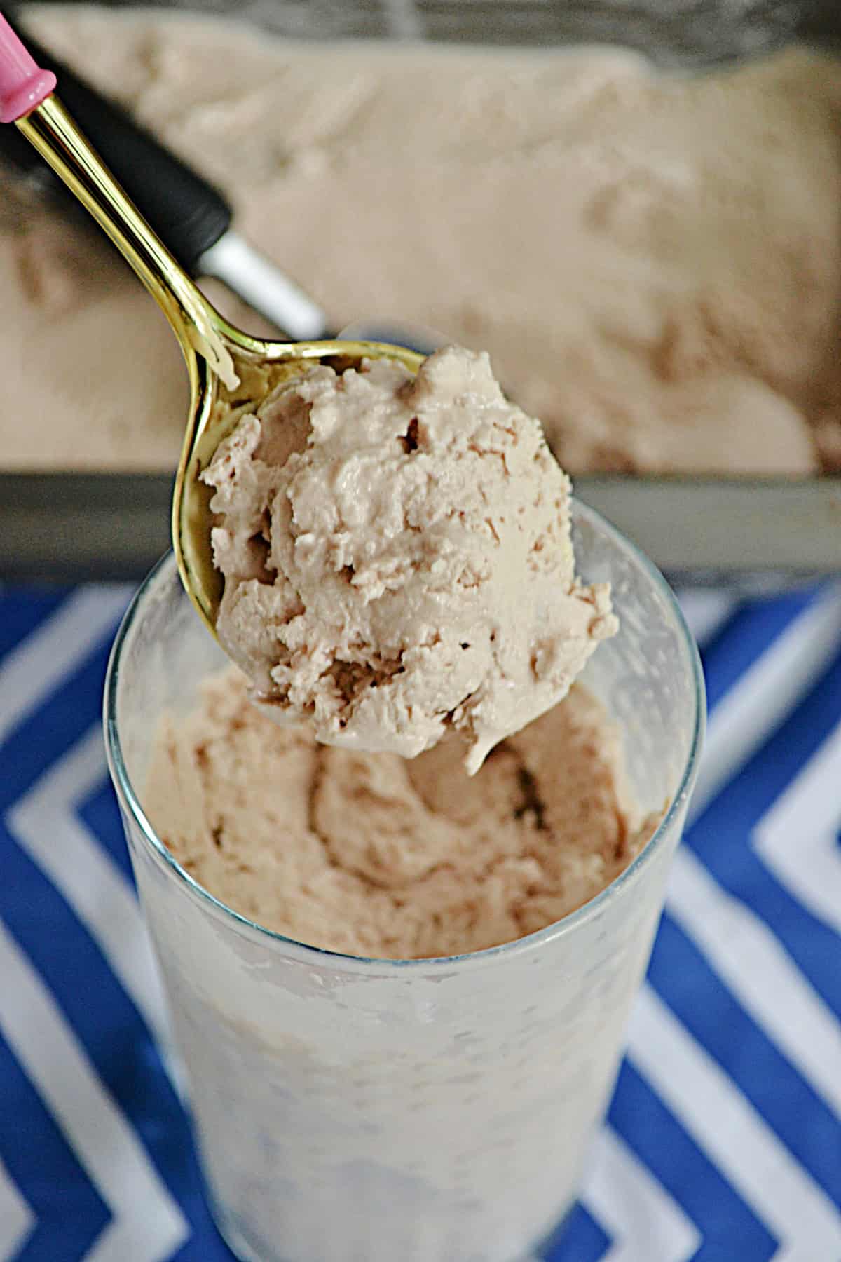 A hand holding a spoon of the frozen chocolate ice cream treat over top of a glass.
